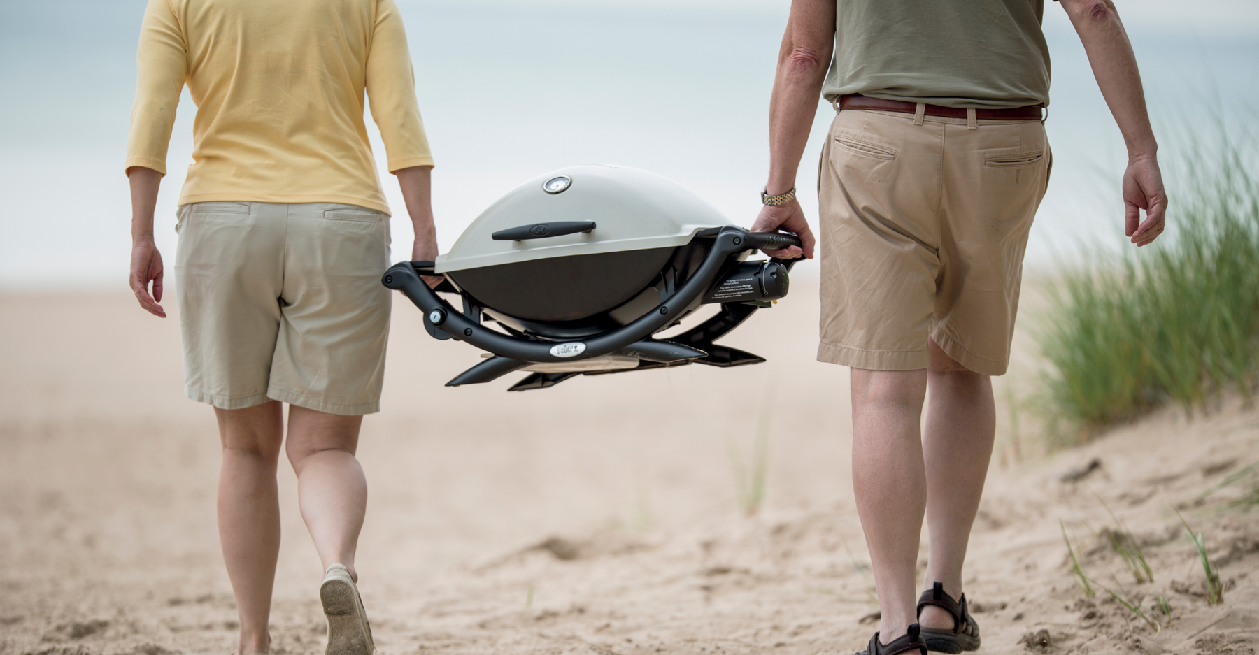 Couple carrying a Weber Q 2200 Propane Portable Grill