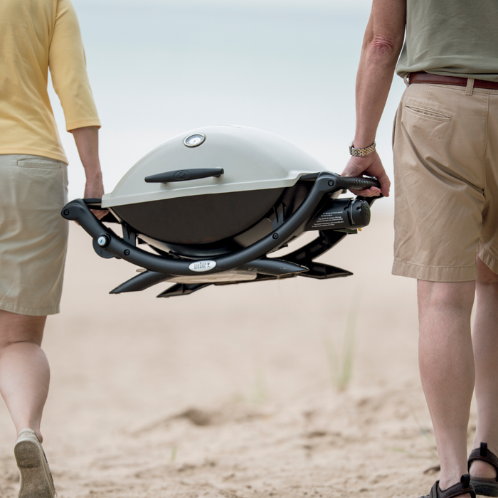 Couple carrying a Weber Q 2200 Propane Portable Grill